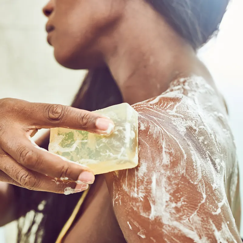 Woman lathering a clear handmade bar on her shoulder