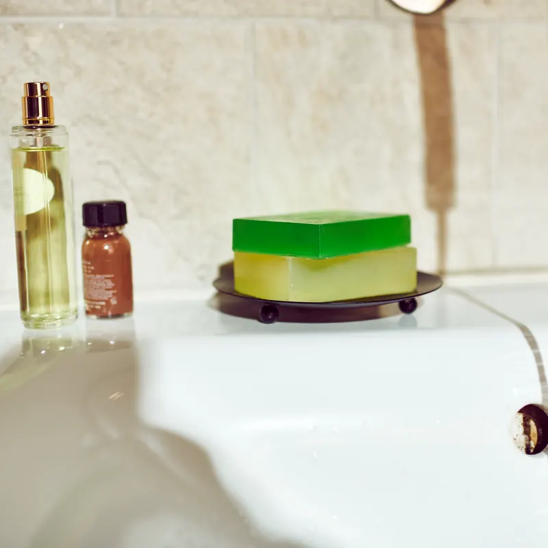 Clear glycerin soap bars on a raised dish by a bathroom sink