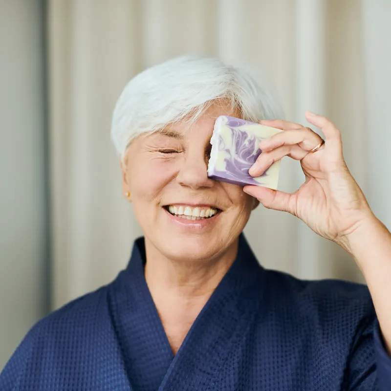 Smiling woman holding a handmade bar over one eye