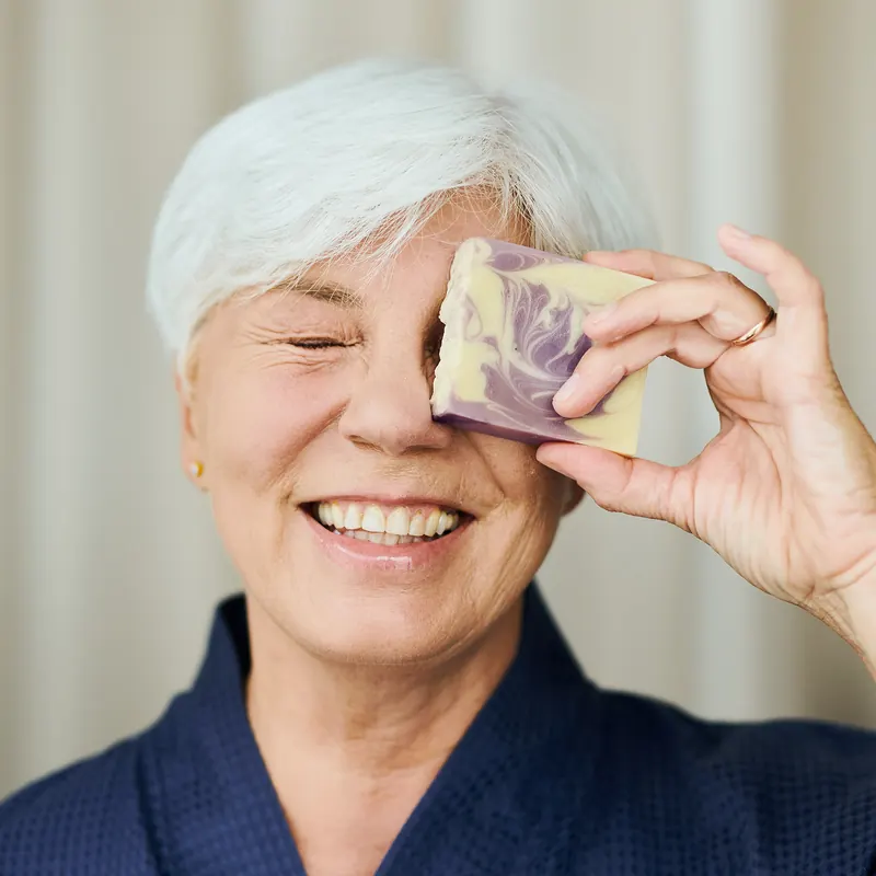 Smiling woman holding a handmade bar over one eye