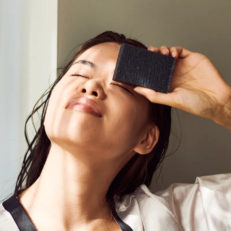 Woman holding a dark handmade bar to her forehead