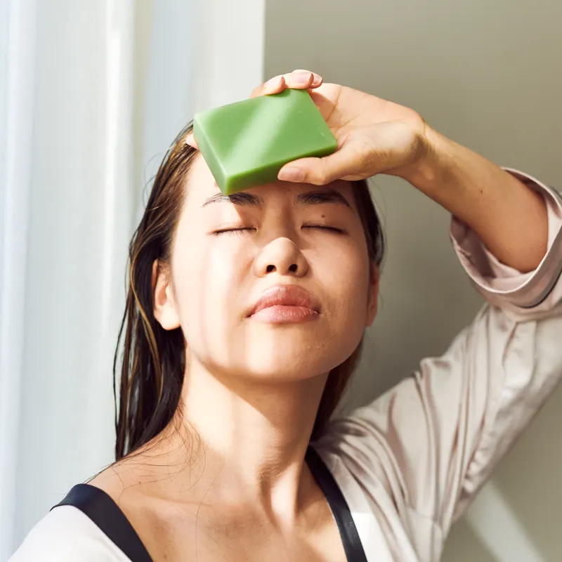 Woman holding a green handmade bar to her forehead