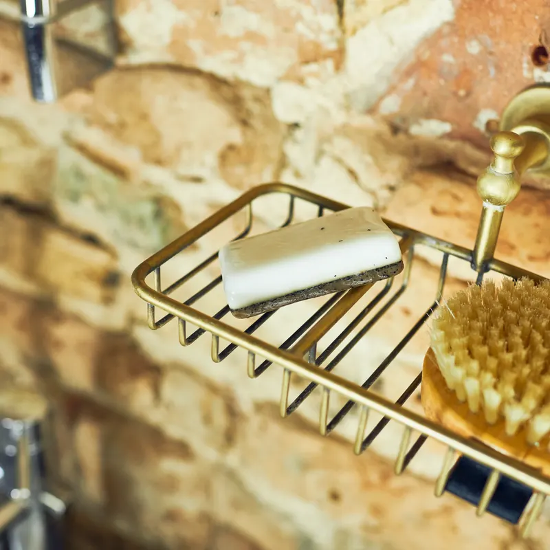 Handmade bar in a brass soap rack by the bath