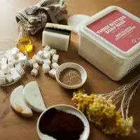Three butters soap base tub on a table with soap cubes and botanicals