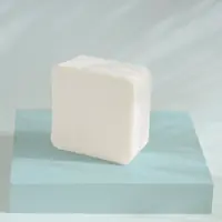 A block of goat milk soap base on a blue stand
