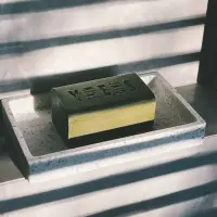 Olive oil soap bar on a stone soap dish in window light