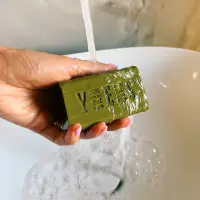Olive oil soap bar held under running water