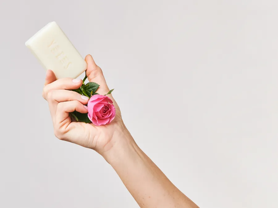 Hand holding a soap bar and a pink rose