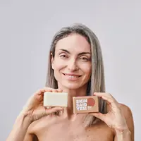 Smiling woman holding an organic soap bar and its carton