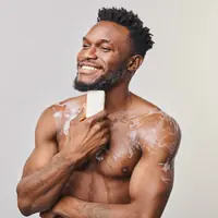 Smiling man lathering an organic soap bar on his chest